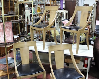 May include: Four wooden chairs with black leather seats. The chairs have a curved back and are arranged on a white table.