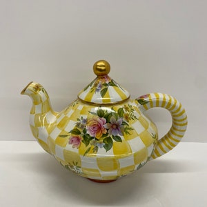 May include: A yellow and white checkered teapot with a floral design and a gold knob on the lid.