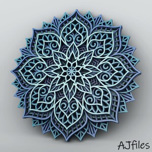 May include: A layered, three-dimensional mandala in shades of blue, teal, and purple. The intricate design features floral and geometric patterns, with a central star-like element. The artwork is set against a neutral gray background.
