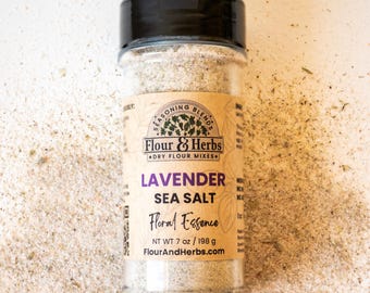 Può includere: Una bottiglia di plastica trasparente di sale marino alla lavanda con coperchio nero. L'etichetta recita "Flour & Herbs" e "Floral Essence". Il peso netto è di 198 g. La bottiglia è su una superficie chiara.