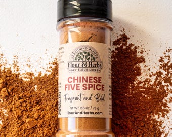Może przedstawiać: Szklany słoik z mieszanką chińskich przypraw pięciu smaków, oznaczony etykietą "Flour & Herbs" z tekstem "Fragrant and Bold" i "NT WT 2.6 oz / 73 g". Słoik stoi na brązowych przyprawach.