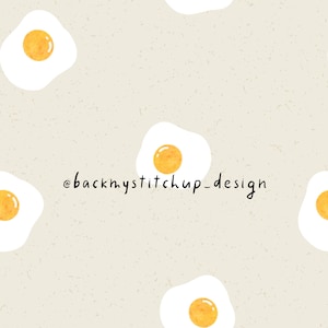May include: A repeating pattern of fried eggs on a speckled beige background. Each egg has a white oval and a yellow yolk. The text "@backmystitchup_design" is written in black cursive font.