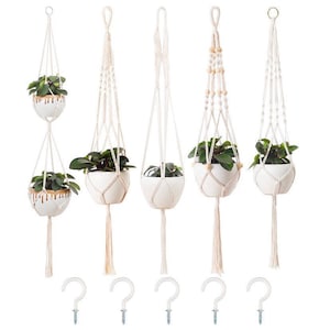 May include: A collection of five macrame plant hangers, each holding a white ceramic pot with a green plant. The hangers vary in design, with some featuring wooden beads. Includes five white metal hooks for hanging.