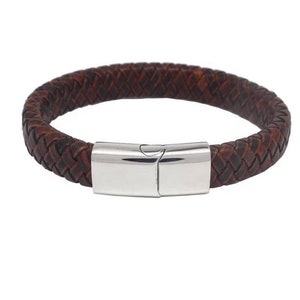 May include: Braided brown leather bracelet with a polished silver clasp. The bracelet features a woven design and a magnetic clasp. This accessory is a stylish addition to any jewelry collection.