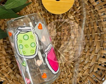 May include: A clear glass tumbler with a lid and straw. The tumbler has a design of jars with hearts and a green jar with cucumbers.