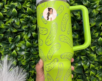 May include: A green stainless steel tumbler with a handle and a lid. The tumbler has a pattern of black and white pickle drawings on it.