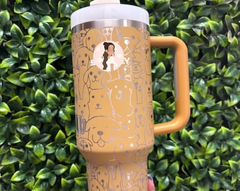 May include: A gold stainless steel tumbler with a clear lid and a straw. The tumbler has a design of dogs all over it. The tumbler has a handle on the side.