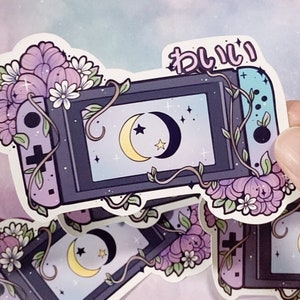 May include: A sticker featuring a stylized illustration of a Nintendo Switch console with a floral design and crescent moons. The text "kawaii" is written in Japanese on the sticker.