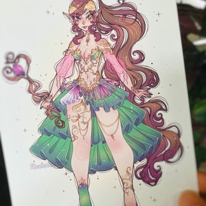 May include: A digital illustration of a character with long brown hair, pointed ears, and a staff topped with a purple crystal. The character wears a green and pink ruffled skirt, a gold-detailed bodice, and matching gold leg ornaments.