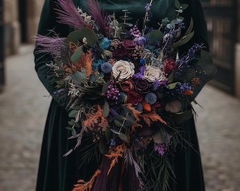 May include: A dark green velvet dress with a square neckline paired with a large, textured bouquet of dried flowers in shades of deep purple, burgundy, burnt orange, and blue, featuring eucalyptus leaves, pampas grass, and various dried blooms.