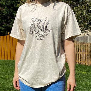 beige t-shirt med handtryckt design och blocktryck i guldfisk