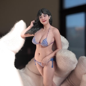 May include: A figurine of a person in a blue and white patterned bikini. The figure has dark hair and is posed with one hand in their hair. The bikini has blue ties. The figurine is held by a gloved hand.