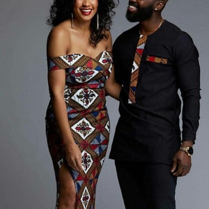 Könnte beinhalten: Eine Frau in einem schulterfreien Kleid und ein Mann in einem langärmeligen Hemd, beide in passendem afrikanischem Stoff. Das Kleid ist ein Etuikleid mit hohem Schlitz. Das Hemd des Mannes hat eine dekorative Blende.