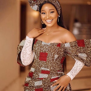 May include: An off-the-shoulder dress and matching head wrap. The dress features a geometric pattern in brown, red, and white. The sleeves are white lace. The woman is wearing gold earrings and a necklace.