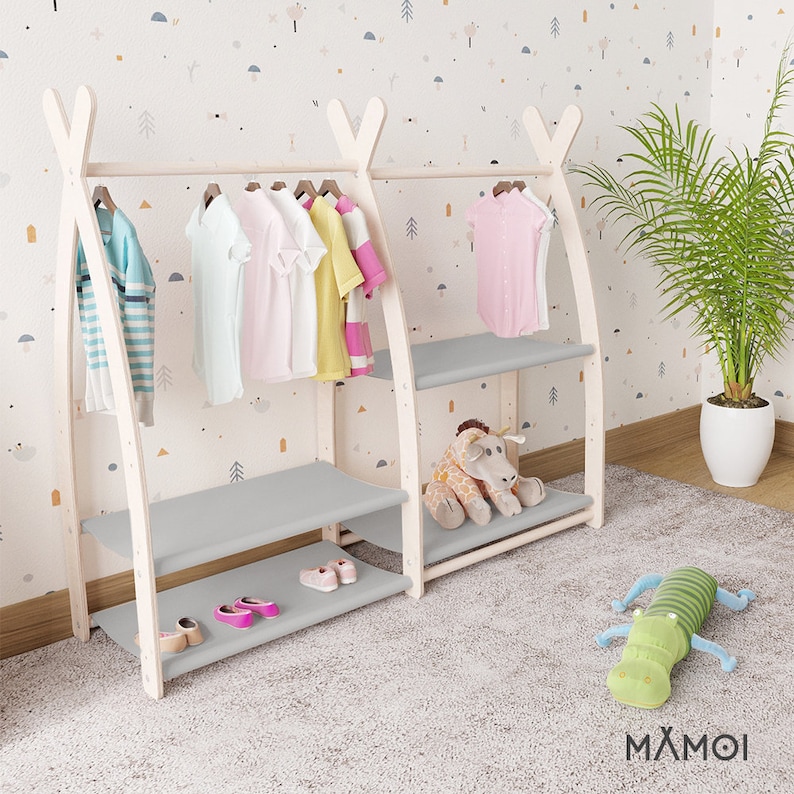 May include: White wooden clothing rack with two shelves and a hanging bar. The rack has a gray fabric shelf and a gray fabric bottom shelf. The rack is decorated with a stuffed giraffe and a stuffed alligator. The rack is labeled with the text "MAXMOI".