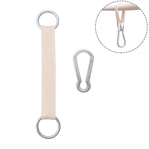 Puede incluir: Un conjunto de componentes de hardware para colgar, que incluye una correa de tela beige con anillos plateados, un mosquetón plateado y un primer plano de una configuración similar. Diseñado para una fijación y suspensión seguras.