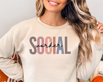 May include: A beige sweatshirt with the text "SOCIAL worker" printed in colorful letters. The letters are in shades of pink, purple, blue, and gray.
