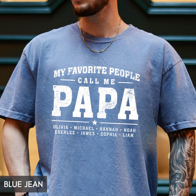 A man wearing a blue t-shirt with the text "MY FAVORITE PEOPLE CALL ME PAPA" printed on it.