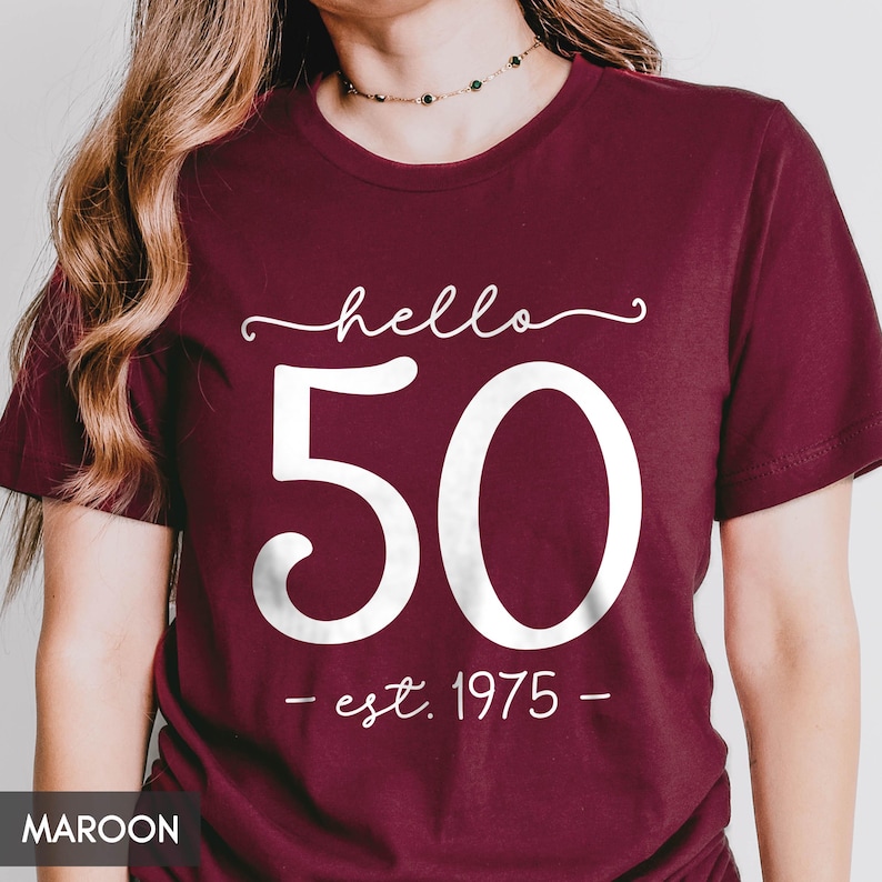 May include: Maroon t-shirt with white text that says "hello 50 - est. 1975 -"