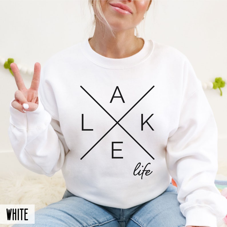 May include: White sweatshirt with a black graphic design that says "LAKE life" with the letters forming a cross.