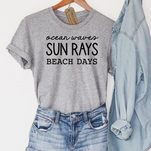 May include: Gray t-shirt with the text "ocean waves SUN RAYS BEACH DAYS" in black lettering.