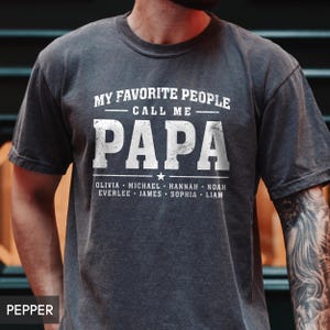 A man wearing a gray t-shirt with the text "MY FAVORITE PEOPLE CALL ME PAPA" printed on it.