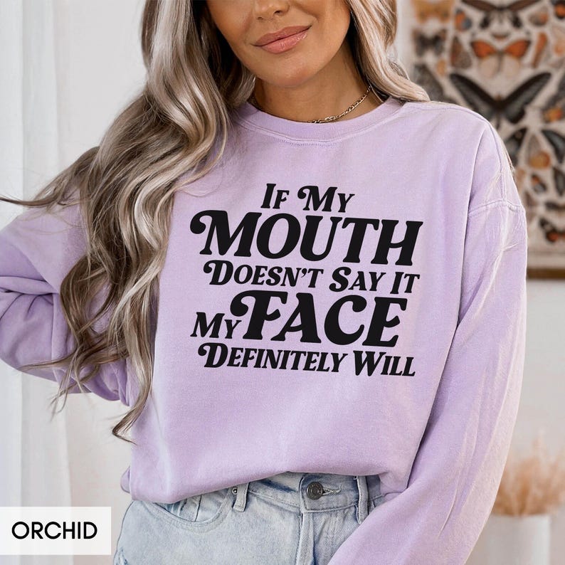Puede incluir: Sudadera color orqu&iacute;dea con el texto negro "If My Mouth Doesn't Say It My Face Definitely Will". La sudadera es de cuello redondo.