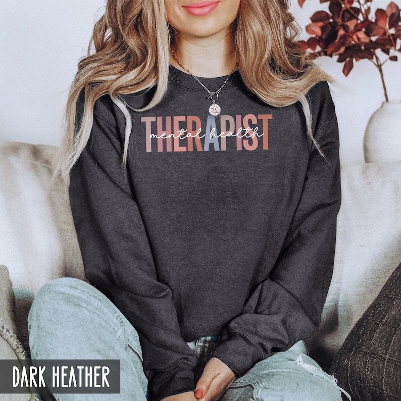 May include: A dark heather grey sweatshirt with the text "THERAPIST mental health" in colorful lettering.