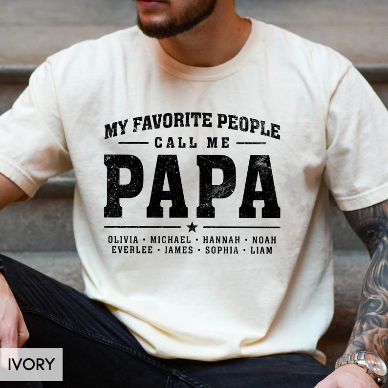 A man wearing a white t-shirt with the text "MY FAVORITE PEOPLE CALL ME PAPA" printed on it.