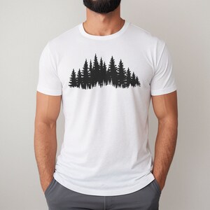May include: A white t-shirt with a black silhouette of a forest on the front.