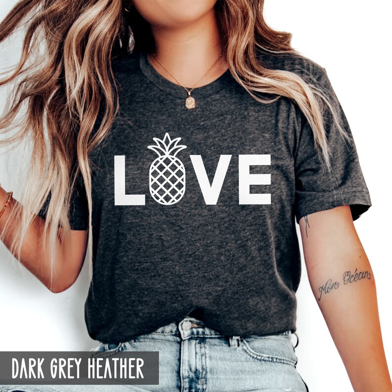 May include: A dark grey heather t-shirt with the word "LOVE" in white text. A white pineapple graphic is in the center of the word "LOVE".