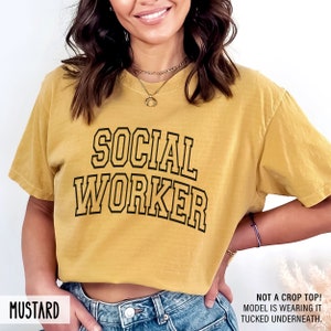 Puede incluir: Camiseta amarilla mostaza con el texto "SOCIAL WORKER" en letras negras.