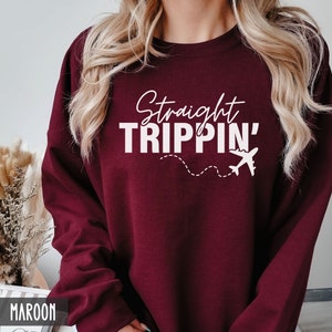 Puede incluir: Una sudadera color burdeos con el texto "Straight Trippin'" en blanco, que incluye un gr&aacute;fico de avi&oacute;n blanco con un rastro de l&iacute;nea punteada.