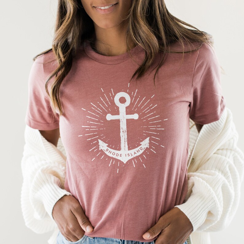 May include: A dusty rose coloured t-shirt with a white anchor graphic and the text "Rhode Island" in a circle around the anchor.