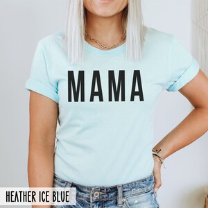 May include: A light blue t-shirt with the word "MAMA" printed in black on the front. The shirt is made of a soft, comfortable material and has a relaxed fit.