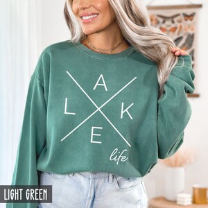 May include: A light green sweatshirt with a white graphic that says "LAKE life" with the letters forming a cross.