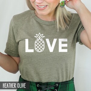 May include: A heather olive t-shirt with a white pineapple graphic and the word "LOVE" printed on the front.