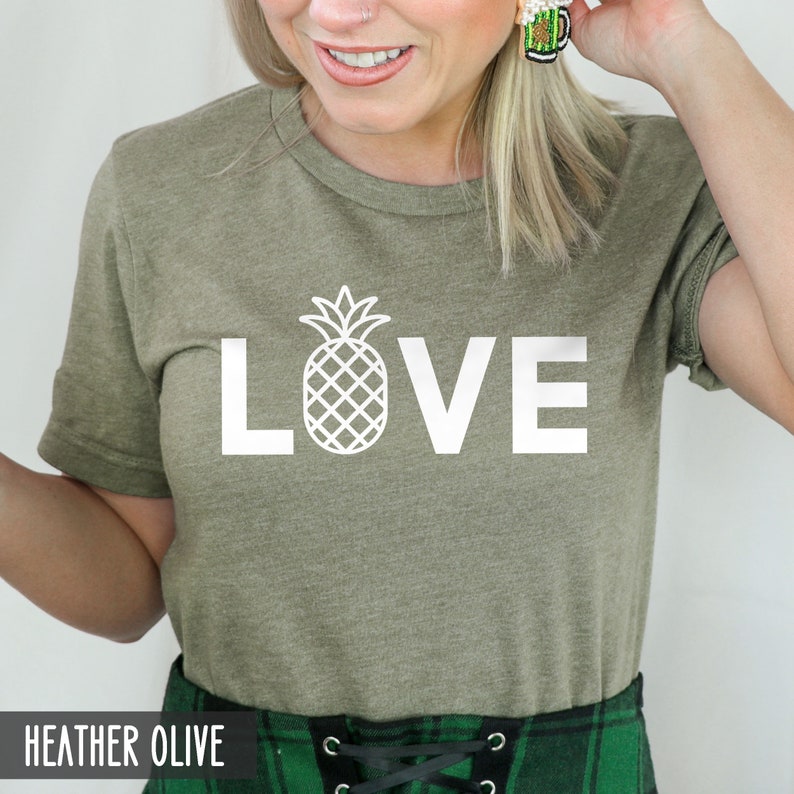 May include: A heather olive t-shirt with a white pineapple graphic and the word "LOVE" printed on the front.