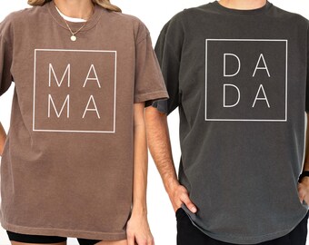 May include: Two oversized t-shirts, one brown with "MAMA" printed in white, and one dark gray with "DADA" printed in white. The shirts are shown on models, with the brown shirt labeled "ESPRESSO" and the gray shirt labeled "PEPPER".