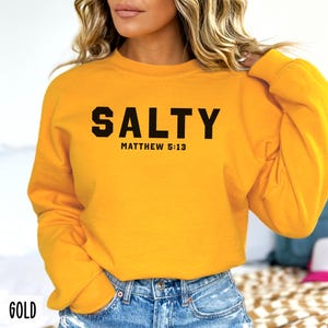 May include: A yellow sweatshirt with black text that reads "SALTY" and "MATTHEW 5:13".