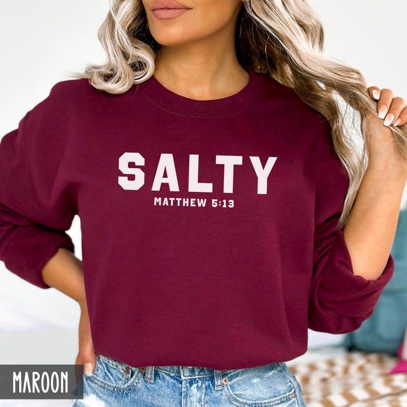 May include: A maroon sweatshirt with the text "SALTY" in white letters and the words "MATTHEW 5:13" in smaller white letters below.