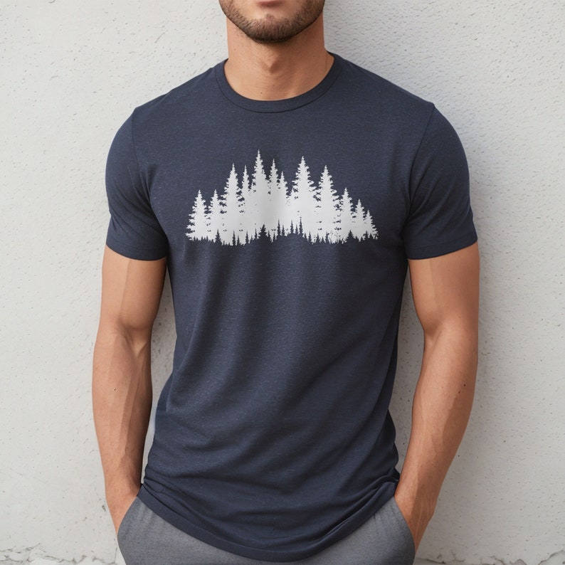 May include: A navy blue t-shirt with a white silhouette of a forest on the front.