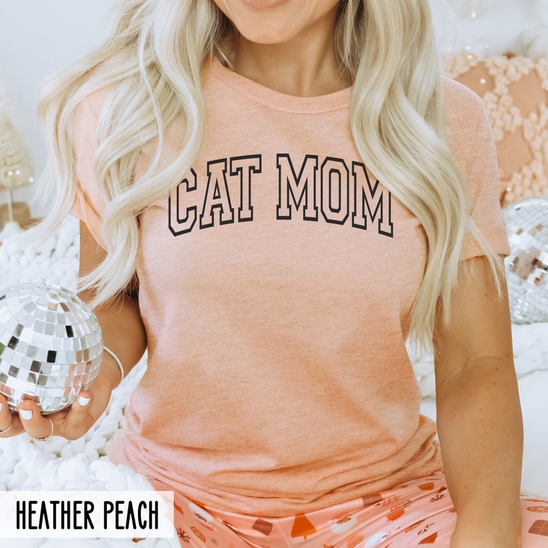 May include: A peach coloured t-shirt with the text "CAT MOM" in black outlined letters.