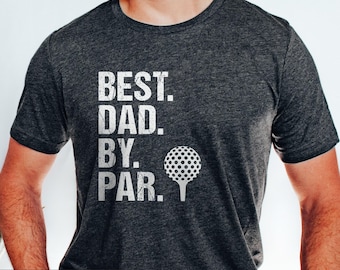 May include: A dark grey heather short-sleeve t-shirt featuring white distressed text that reads BEST. DAD. BY. PAR. accompanied by a white graphic of a golf ball on a tee. The shirt has a crew neckline and a standard fit for casual wear.