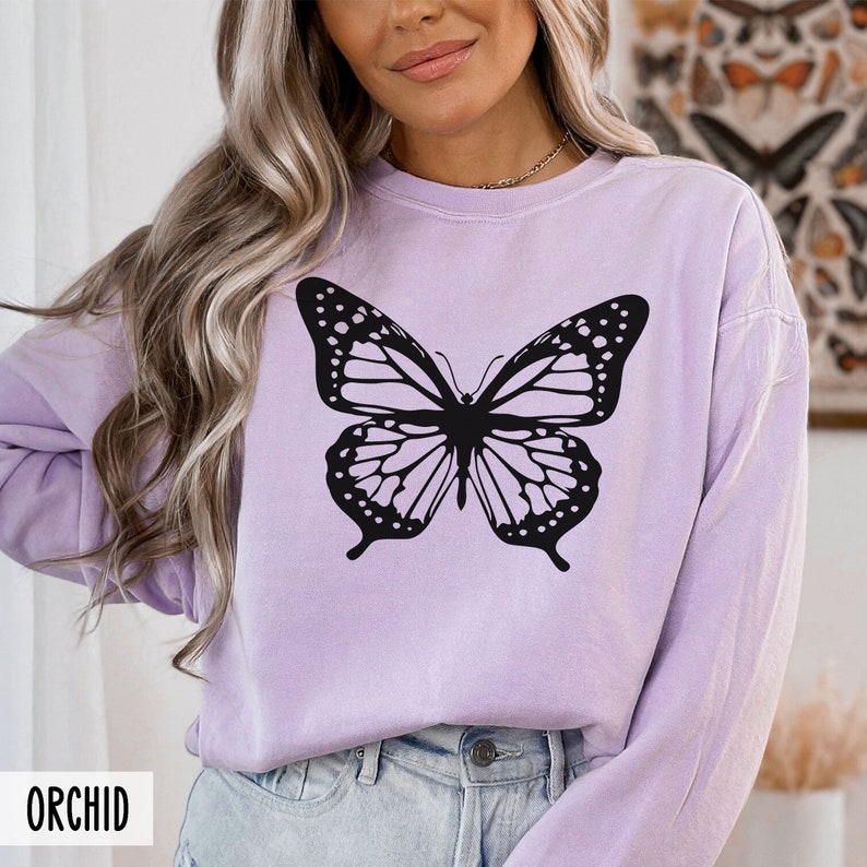 Peut inclure: Un t-shirt &agrave; manches longues de couleur lavande avec un motif de papillon noir. Le t-shirt a une coupe d&eacute;contract&eacute;e et un col rond.