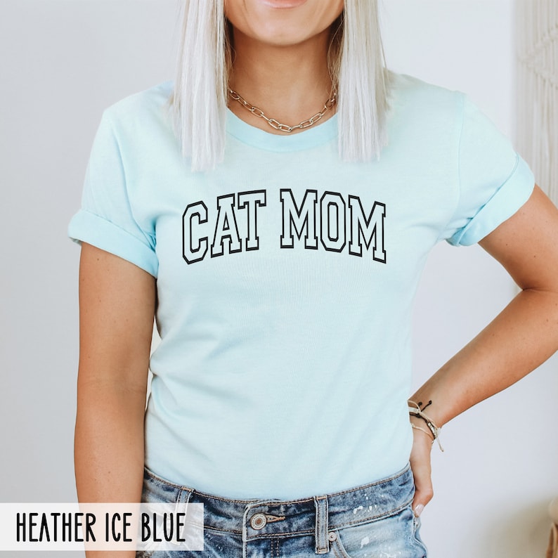 May include: A light blue t-shirt with the text "CAT MOM" in black outlined letters.