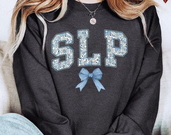 May include: Dark heather grey sweatshirt with a floral design spelling out "SLP" and a blue bow.