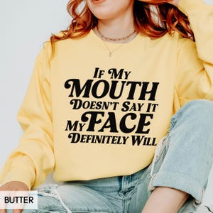 Puede incluir: Sudadera de color mantequilla con el texto negro "If My Mouth Doesn't Say It My Face Definitely Will". La sudadera de manga larga tiene cuello redondo. La palabra "BUTTER" est&aacute; en la esquina inferior izquierda.