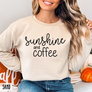 May include: A beige sweatshirt with the text "sunshine and coffee" printed in black.
