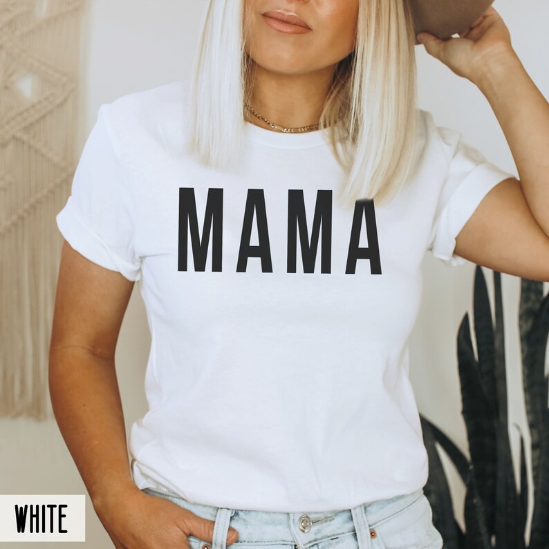 May include: White t-shirt with the word "MAMA" printed in black on the front.
